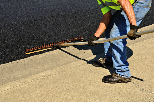 Worker,Using,A,Rake,To,Push,Excess,Asphalt,Off,Of
